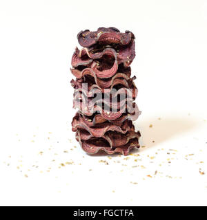 Une pile de chips de betterave ronde fine cuit au four avec l'origan et le sel empilées sur fond blanc. Un sain, végétarien, v Banque D'Images