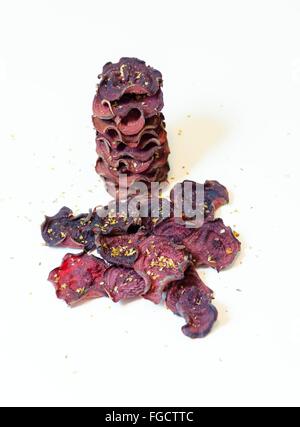 Une pile de chips de betterave ronde fine cuit au four avec l'origan et le sel empilées sur fond blanc. Un sain, végétarien, v Banque D'Images