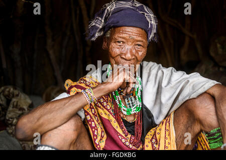 Portrait d'une vieille femme de la tribu des bushmen à l'intérieur de sa hutte dans une partie reculée du désert du Kalahari. Banque D'Images