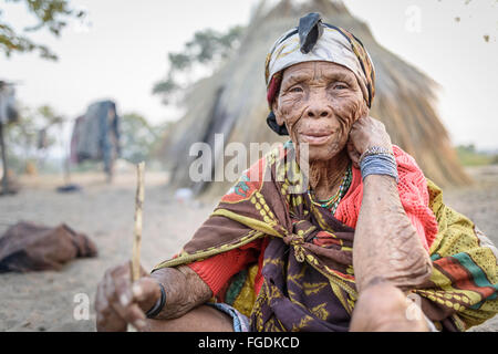 Portrait d'une vieille femme de la tribu des bushmen devant sa hutte faite d'herbe. Banque D'Images