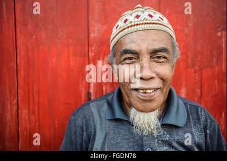 Portrait d'un homme barbu blanc devant un mur rouge. Banque D'Images