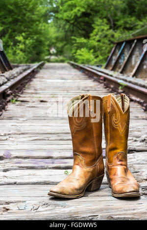 Bottes de cow-boy sur un vieux pont de chemin de fer. Banque D'Images