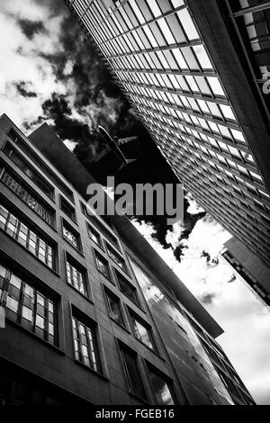 Image en noir et blanc à la recherche d'un avion à travers le ciel en direction de tours de bureaux à Liverpool Banque D'Images