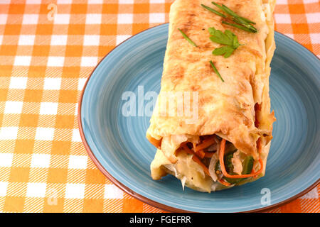 Burrito avec tomates et fromage sur la plaque bleue Banque D'Images