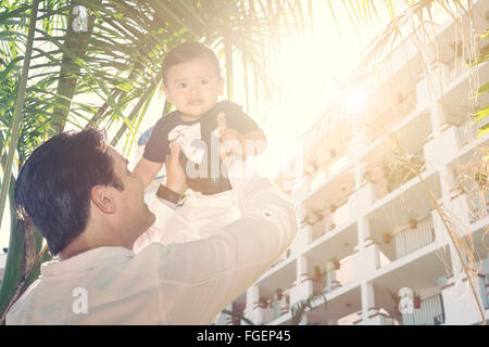 Man lifting son fils en l'air contre le soleil. Photographie de rétroéclairage. Banque D'Images