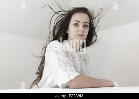 Femme assise à table avec perdus et une expression grave Banque D'Images