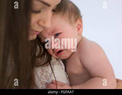 Mother holding baby fils dans les bras en pleurs, avec une unique larme qui sortent de son oeil Banque D'Images