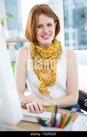 Hipster smiling woman sitting at a desk Banque D'Images