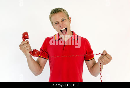 Homme tenant un téléphone rétro rouge hurlant Banque D'Images
