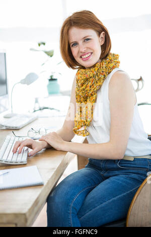 Hipster smiling businesswoman sitting at her desk Banque D'Images