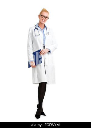 Full Length portrait of female doctor standing contre fond blanc tout en maintenant le presse-papiers dans ses mains et souriant à la c Banque D'Images