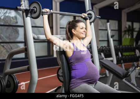 Smiling pregnant woman lifting barbell Banque D'Images