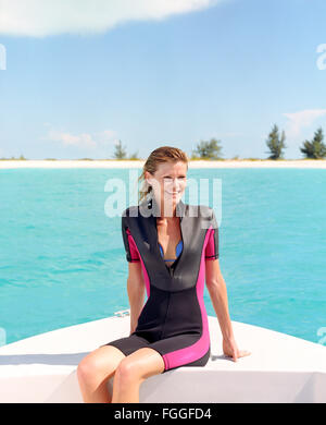 Une jeune femme sites sur un bateau avant la plongée.Providenciales, Îles Turques et Caïques. Dans les Caraïbes. Banque D'Images