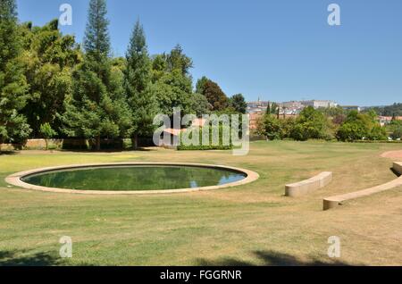 Sièges en pierre autour d'étang dans les jardins de Quinta das Lagrimas avec vue sur la ville de Coimbra, Portugal Banque D'Images