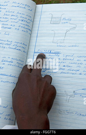 À partir de la lecture des enfants ougandais, à l'aide de matériaux pédagogiques doigt pour suivre les lignes. Banque D'Images