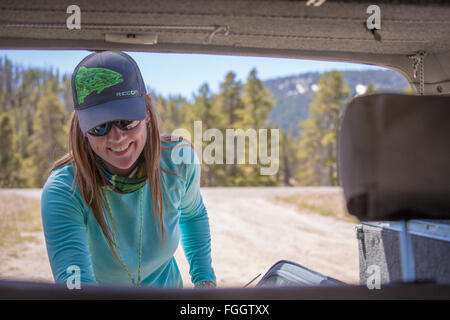 Femme de forage les tiges de mouche à l'arrière d'un Land Cruiser avant la pêche. Banque D'Images