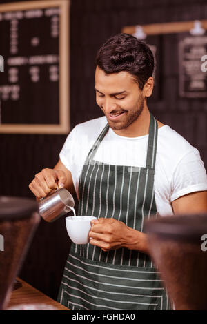 Handsome waiter adjonction de lait au café Banque D'Images