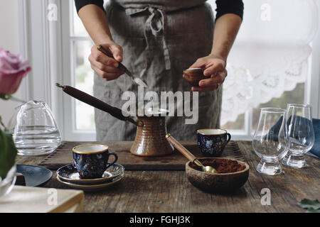 Une femme est de placer le sucre dans une petite casserole pour faire le café turc. Banque D'Images