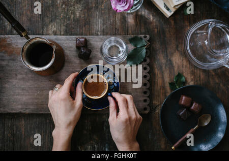 Une femme tient une tasse de café turc avec de la mousse sur le dessus (avec les deux mains) qui est servi avec de l'eau et de chocolat. Photograp Banque D'Images