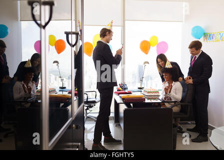 Business Woman celebrating birthday et faire une fête avec des collègues de son bureau. Un ami avec un téléphone mobile prend des photos o Banque D'Images