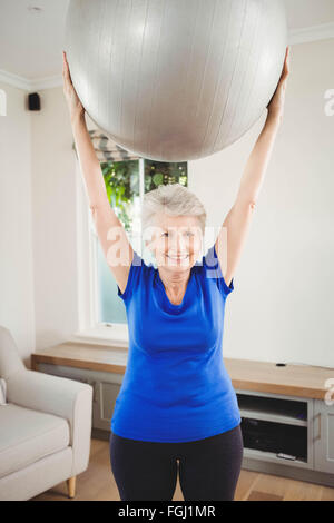Senior woman lifting boule d'exercice pendant l'exercice de Banque D'Images