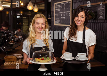 Jolies serveuses posant devant le comptoir café présentant et pie Banque D'Images