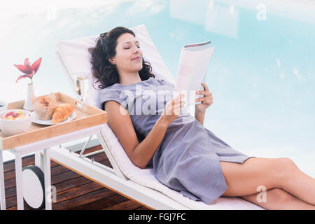 Young woman reading magazine près de poolside Banque D'Images