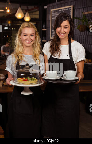 Jolies serveuses posant devant le comptoir café présentant et pie Banque D'Images