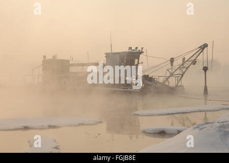 Un remorqueur bateau dans la brume au coucher du soleil d'hiver Banque D'Images