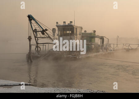 Un remorqueur bateau dans la brume au coucher du soleil d'hiver Banque D'Images