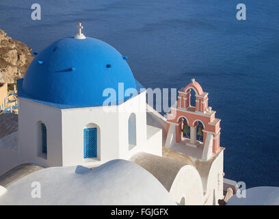 Santorin - Le regard bleu de coupoles de l'église avec le petit clocher à Oia sur la caldeira. Banque D'Images