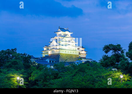 Coucher de soleil coloré ciel derrière l'ancienne Himeji-jo Château s'élevant au-dessus de la limite forestière au soir à Himeji, Japon après rénovations fin 2015 Banque D'Images