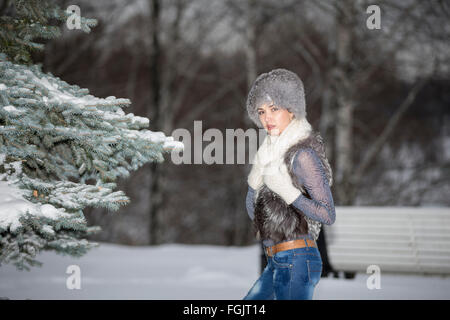 La femme dans une élégante Écharpe contre le bois et la neige en hiver noël Banque D'Images