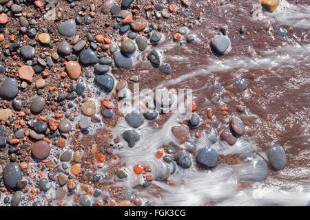 Santorin - Le détail des pemza de plage rouge dans la vague . Banque D'Images