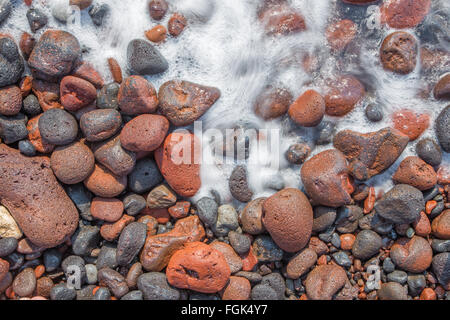 Santorin - Le détail des pemza de plage rouge dans la vague . Banque D'Images