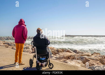 Fuengirola, Malaga, Andalousie, espagne. 20 Février, 2016. Météo : Code orange est donnée pour de hautes vagues et le vent. Un couple sur la jetée en regardant l'état de la mer et des surfeurs Banque D'Images