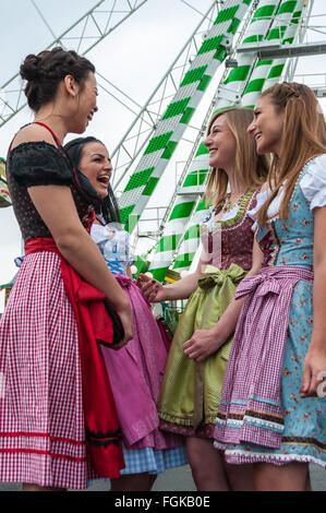 Jolie femme joyeuse et à l'Oktoberfest dirndl traditionnel allemand avec des robes, grande roue à l'arrière-plan. Banque D'Images