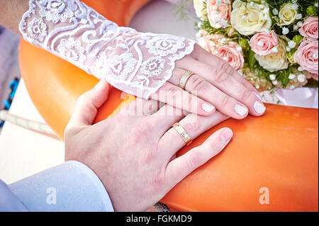 Les mains des mariés avec des anneaux sur un magnifique bouquet de mariage Banque D'Images