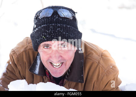 Portrait of a smiling man ludique rassemblant une brassée de neige à deux pas Banque D'Images