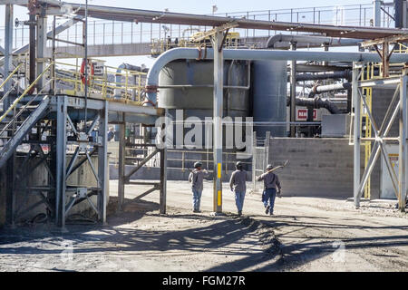 3 mineurs avec picks sur route à travers les tuyaux massive enchevêtrement de convoyeurs cuves adjacente à l'usine de cuivre de la mine mission Arizona Banque D'Images