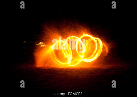 Le feu et le feu pétille de traces de feu dansant sur la plage prise en utilisant la technique d'exposition longue. Banque D'Images