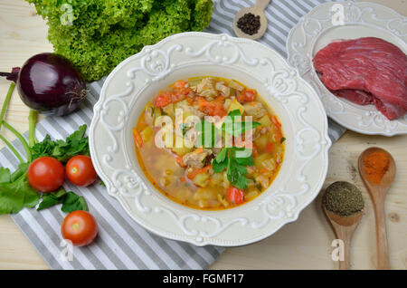 Et de légumes servi dans un plat répondre plaque fine sur la table entourée avec des ingrédients - rencontrez, tomates, oignons, épices et fines herbes Banque D'Images