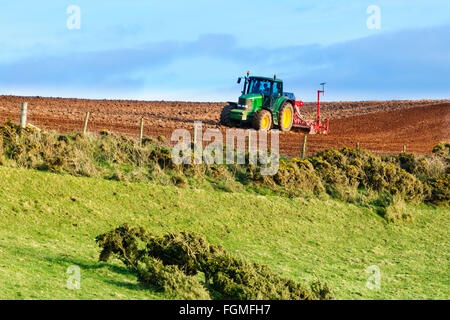 Le tracteur tirant un semoir à travers un champ labouré, montrant les caractéristiques de profondeur, une terre rouge fertile du sud du Devon, Angleterre Banque D'Images
