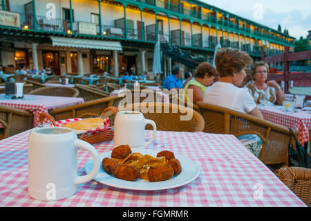 L'Espagnol tapa : croquettes servant et deux pichets de bière en terrasse à la tombée de la nuit. Place principale, Chinchon, province de Madrid, Espagne. Banque D'Images