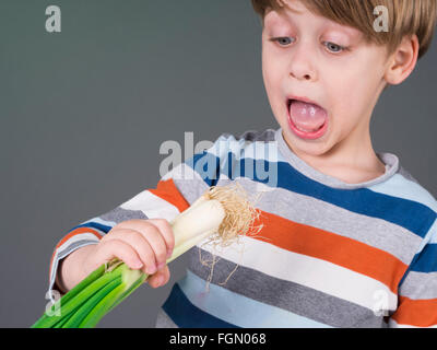 Funny kid holding Légumes Poireaux, refuse de manger Banque D'Images