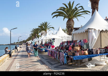 Personnes sur la promenade au bord de l'eau avec les étals de marché de Lagos, Algarve, Portugal Banque D'Images