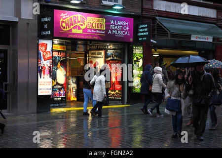 Les gens en passant devant un bureau de réservation de billets de théâtre sur un soir de pluie, près de Covent Garden, Londres, Angleterre Banque D'Images