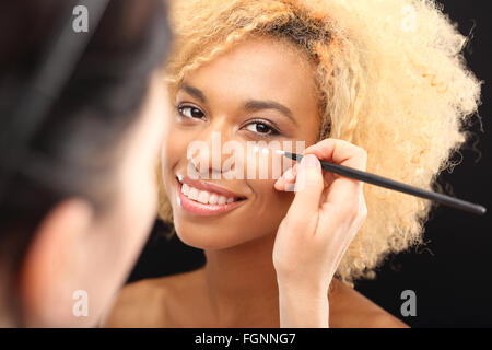 Dark skinned woman's face recouverte de crème glacée sous les yeux. Crème anti rides soin peau délicate autour des yeux Banque D'Images