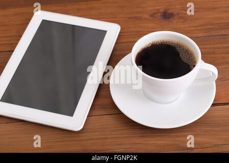 Tablette numérique et tasse de café sur le bureau en bois. Banque D'Images