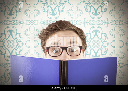 Image composite de geeky student reading a book Banque D'Images